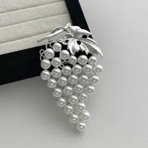 Vintage style grape cluster brooch with silver leaves and white faux pearls on white background