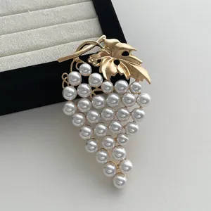 Detailed close-up of vintage grape brooch with golden leaves and round white pearls