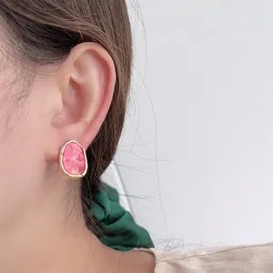 Unregelmäßige rosa Acryl-Ohrringe mit Goldmetallrahmen, von einem Modell getragen