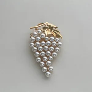 Detailed view of grape brooch with white pearls and vintage gold metal leaf design