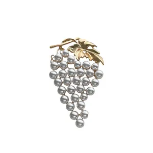 Elegant vintage grape brooch with golden leaves and white pearls on a white background