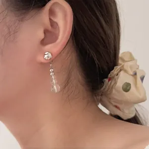 Detailed view of silver-tone hammered metal earrings with transparent beads on ear