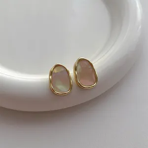 Detailansicht der unregelmäßigen Goldlegierung-Ohrringe mit rosa schillernder Acryl-Einlage