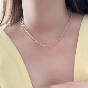 Close-up of pink glass beaded necklace worn by model showing translucent cherry blossom beads