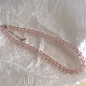 Close-up of pink translucent glass beads and silver extension chain on jewelry