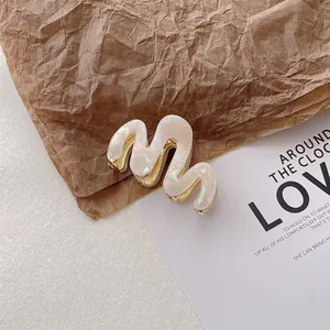 Close-up of wavy cream-white acetate hair claw clip with golden metal accents