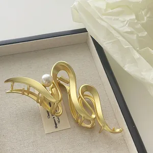 Detailaufnahme der mattgoldenen Metall-Haarklammer mit Perle auf einem Tablett