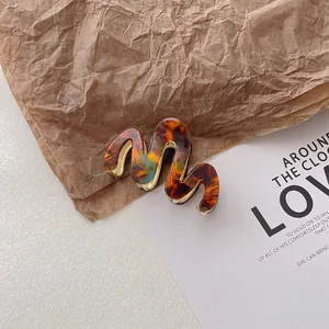 Detail showing wavy acetate hair claw clip with amber tortoiseshell texture and gold metal clip