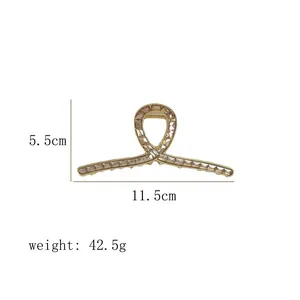 Detail view of gold metal shark hair clip with brown crystals and size measurements