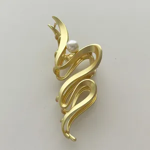 Makroansicht der mattgoldenen Wellen-Haarklammer mit einer weißen Perle und Metallfeder