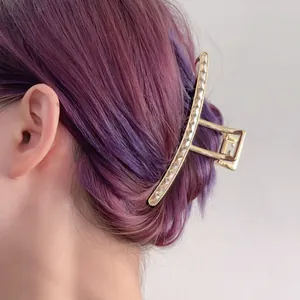 Elegant gold wavy hair claw clip with rhinestones worn on purple gradient hair