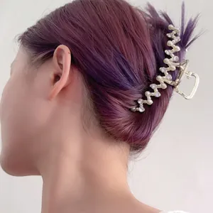 Detailopname van een gouden haarklem met parels en zirkoon op paarsachtig haar