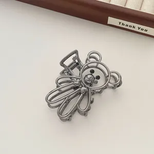 Detalle de pinza para el cabello de oso metálico con diseño calado y mecanismo de resorte