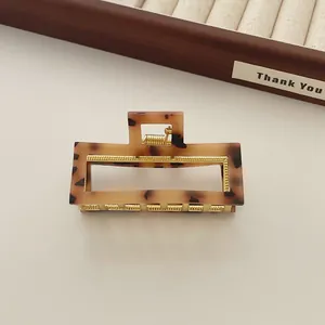 Detail van haarclip van acryl in schildpadmotief met gouden metalen veer en frame