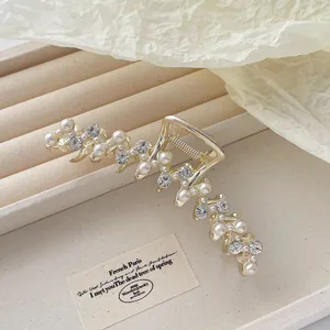 Elegante goudkleurige metalen haarklem met parels en zirkonia in een bladachtig ontwerp
