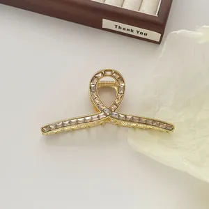 Detailed macro of gold metal hair claw clip with champagne zircons on dark wood