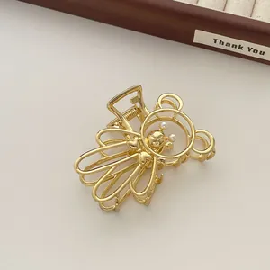 Detalle de la pinza para el pelo de oso metálico dorado con perlas y diseño hueco