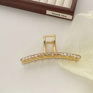 Close-up of golden metal hair claw clip with champagne zircons on wooden jewelry tray