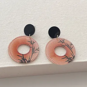 Details von runden Ohrringen mit traditioneller Bambusmalerei und rotem Sonnenmotiv