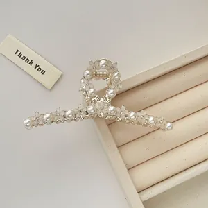 Dettaglio molletta per capelli in metallo dorato con fiori bianchi e perle
