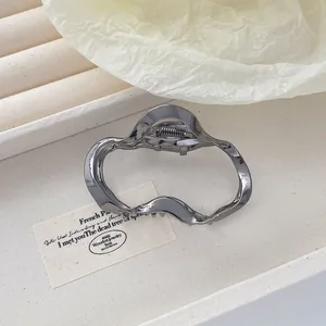 Détail d'une pince à cheveux en métal gris foncé ondulé avec une finition polie