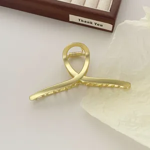 Detailopname van de matgouden haarklem met elegant gedraaid ontwerp op houten dienblad