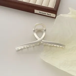 Macro-opname van een matte zilveren metalen haarklem met strak infinity-ontwerp
