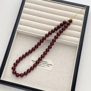 Detail einer tiefroten Perlenkette mit goldenem Karabinerverschluss und Verlängerungskette