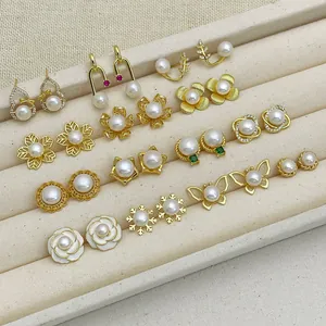 Detailed view of various gold-plated pearl earrings on a beige velvet jewelry display
