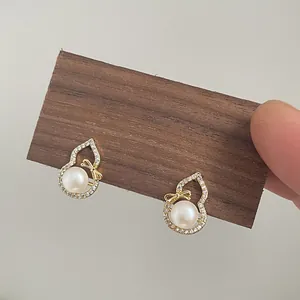 Detail of gold gourd earrings with natural pearls and zircon-encrusted bow design