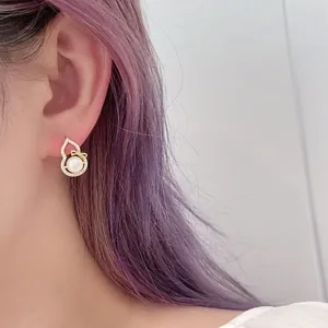 Elegant gold bow earrings with natural freshwater pearls and sparkling zircons on model
