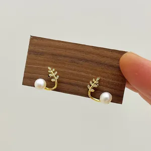 Close-up of elegant gold leaf earrings with natural pearls and pavé cubic zirconia