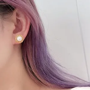Detail of vintage palace style pearl stud earrings with golden lace borders on model