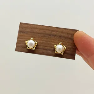 Detailed close-up of a star-shaped gold earring featuring a lustrous white freshwater pearl