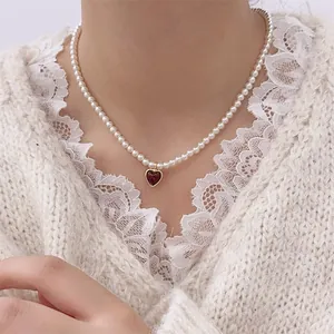 French vintage pearl necklace with red heart pendant and gold metal frame on a model