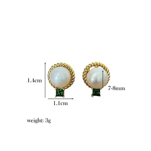 Detail view of pearl earrings with gold twisted borders and green square gemstones