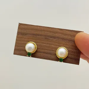 Detailed shot of retro pearl earrings with green stones and gold rope texture edges