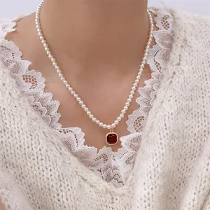 French retro pearl necklace with a red agate pendant and gold metal frame on a woman