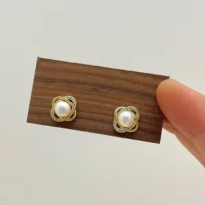 Macro detail of freshwater pearl earrings with gold twisted frame and zircon inlay