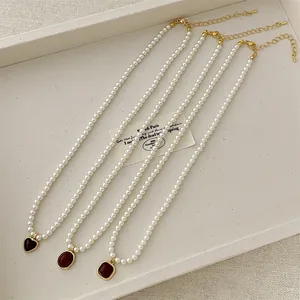 Macro detail of French vintage pearl necklaces with heart, oval and square red stone pendants