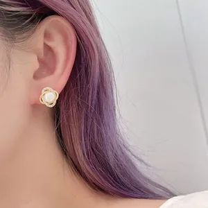 Close-up of geometric gold pearl earrings with zircon inlay worn on a model's ear