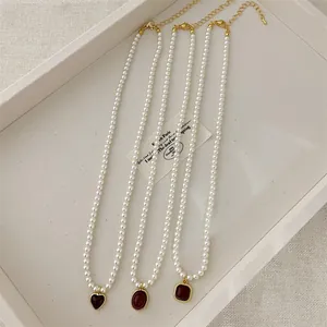 Detailed macro view of white pearl necklaces featuring vintage red agate metal pendants