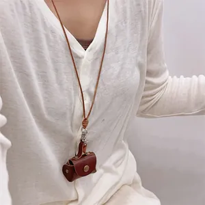 Close-up of a mini brown leather pouch necklace worn as a functional accessory