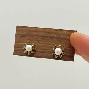Macro view of gold snowflake earrings with central white pearls on a wood display