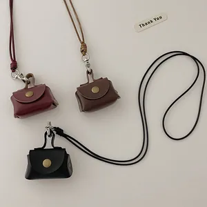 Detailed view of mini leather coin purse pendants in wine red, dark brown, and black colors