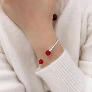 Close-up of a silver C-shaped open cuff bracelet with two elegant red agate beads