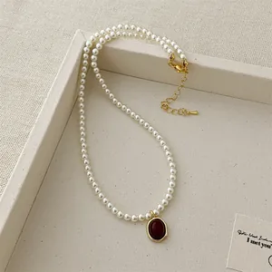 Detail of red agate pendant with gold bezel on a white pearl strand necklace