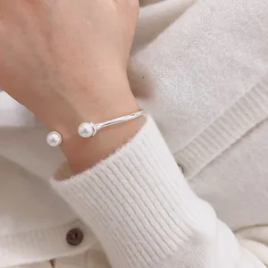 Elegant silver open bangle with white pearls worn over a cozy cream knitted sweater