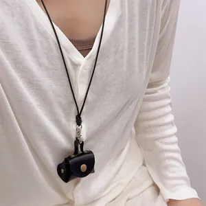 Detail of a mini black leather coin purse necklace with silver hook and gold snap button
