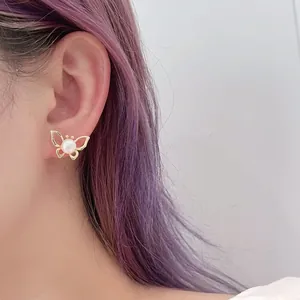Close-up of golden hollow butterfly stud earring with natural freshwater pearl on ear